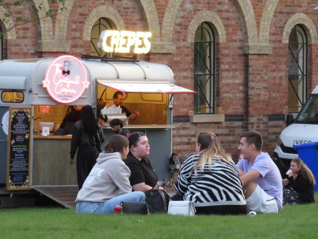 groups of friends sat on lawn with food truck