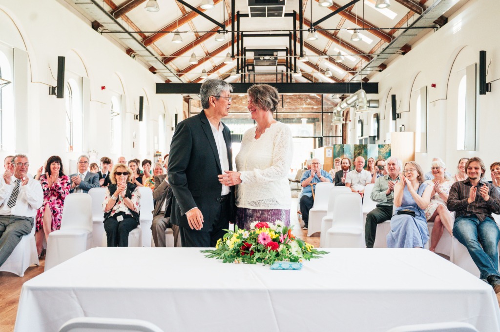 couple at the alter, venue dressed in white with industrial beams above